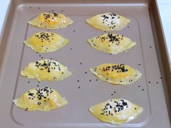 Cho khay bánh tart trứng ra khỏi lò. Gỡ bỏ giấy bạc bọc bên ngoài, xếp các chiếc bánh trứng lên khay nướng. Đánh tan lòng đỏ trứng gà, dùng cọ quét phết đều 1 lớp trứng lên một mặt bánh trứng, rắc chút mè đen. Đặt khay bánh tart trứng nhân xoài trở lại lò nướng ở 185 độ C thêm 10 phút nữa nhé.