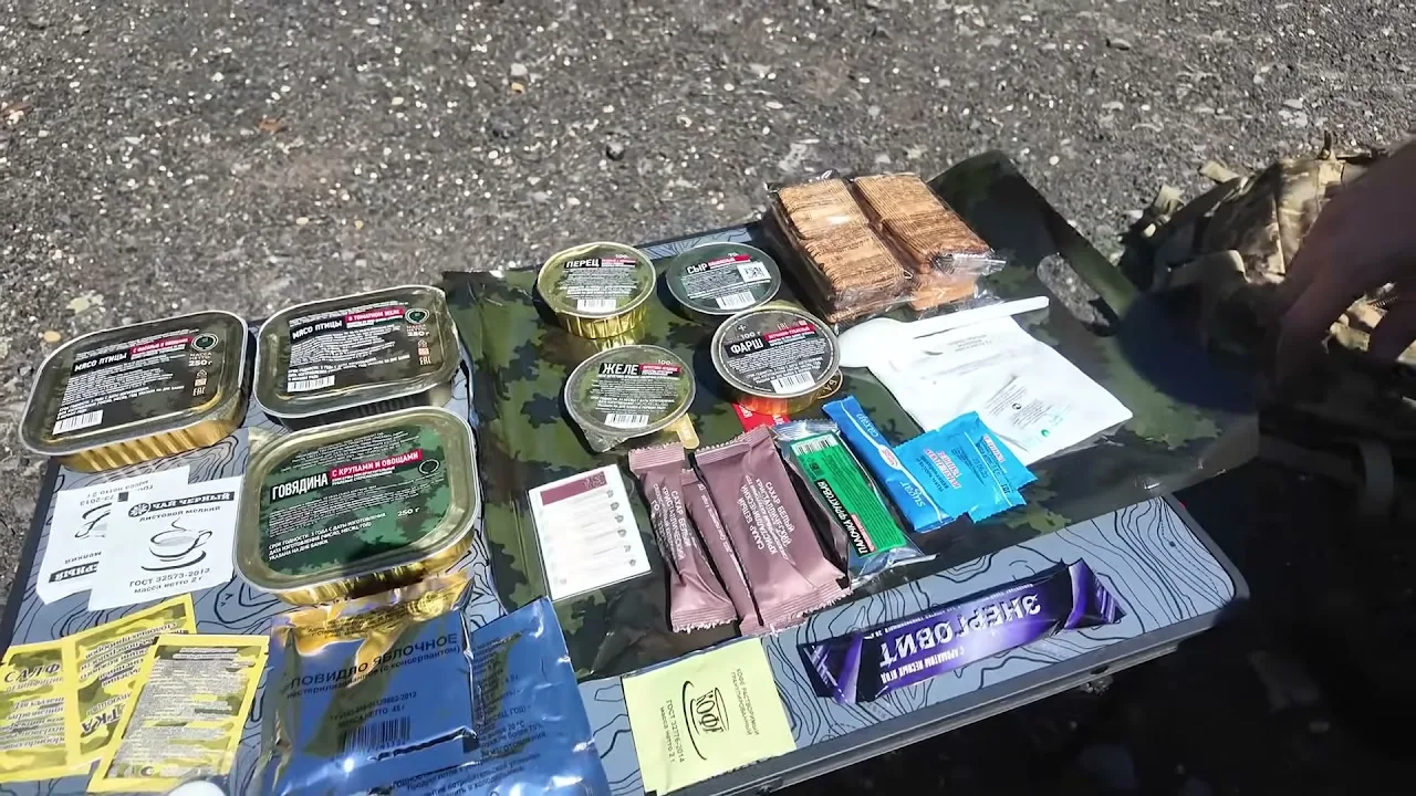 Az orosz 24 órás fejadag teljes tartalma kirakva az asztalra, cirill feliratú konzervekkel
