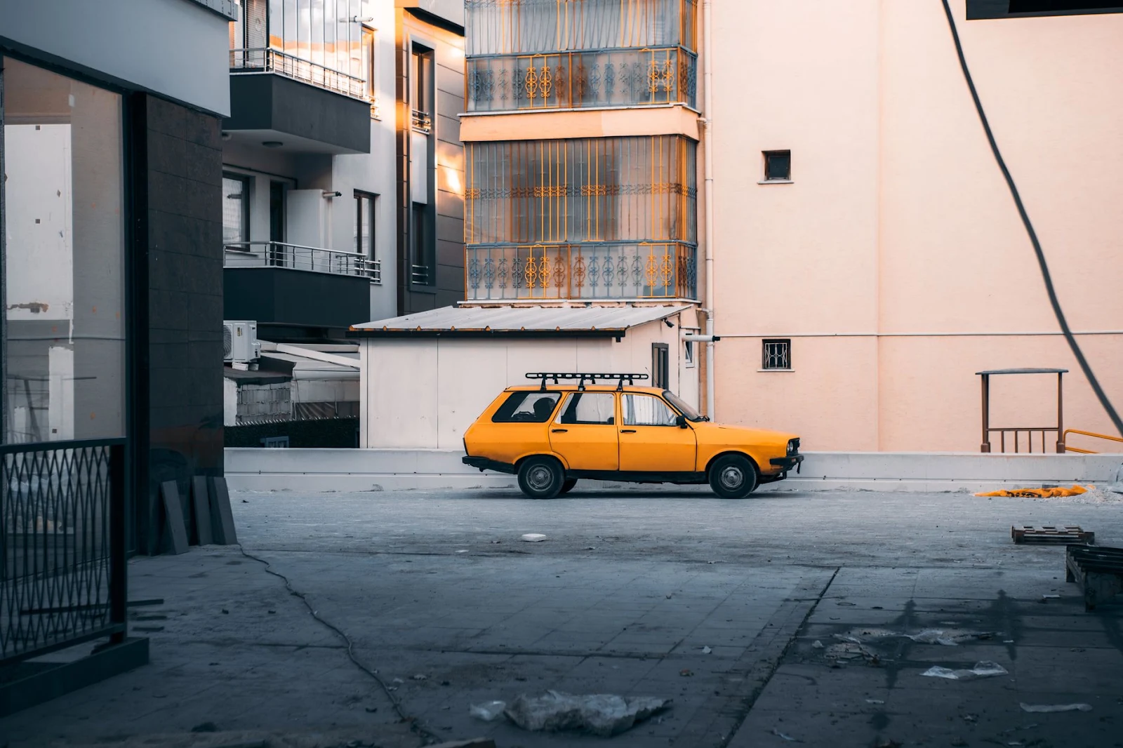 A classic yellow car parked on a quiet urban street in Konya, Türkiye, showcasing architectural contrasts.