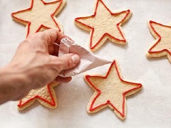 Lấy bánh ra quét lên một lớp kem trắng. Kem màu đỏ có thể dùng để vẻ viền ngôi sao, cũng có thể quét lên như kem màu trắng và màu xanh vậy. Cứ làm như vậy đến hết số bánh và kem.