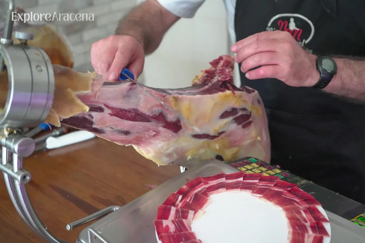 Local jamón carver slicing thin pieces of Jamón Ibérico onto a plate in Aracena.