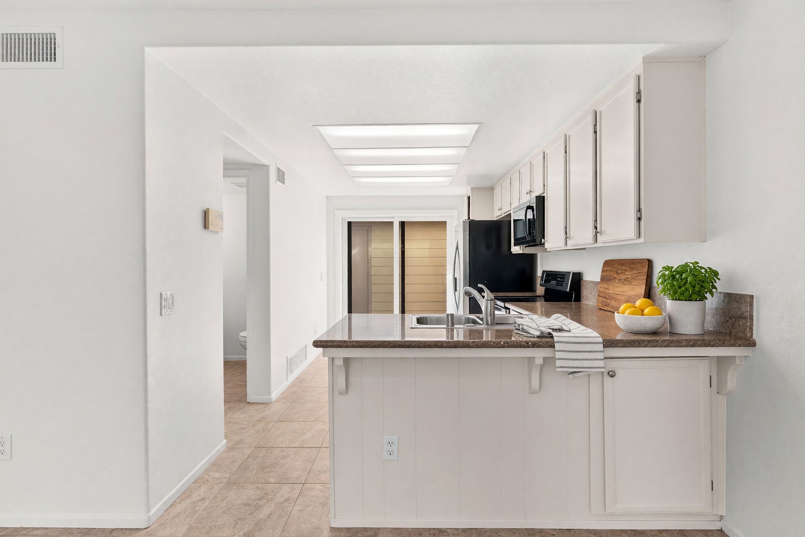 Kitchen with white cabinetry, granite counters, and breakfast bar peninsula