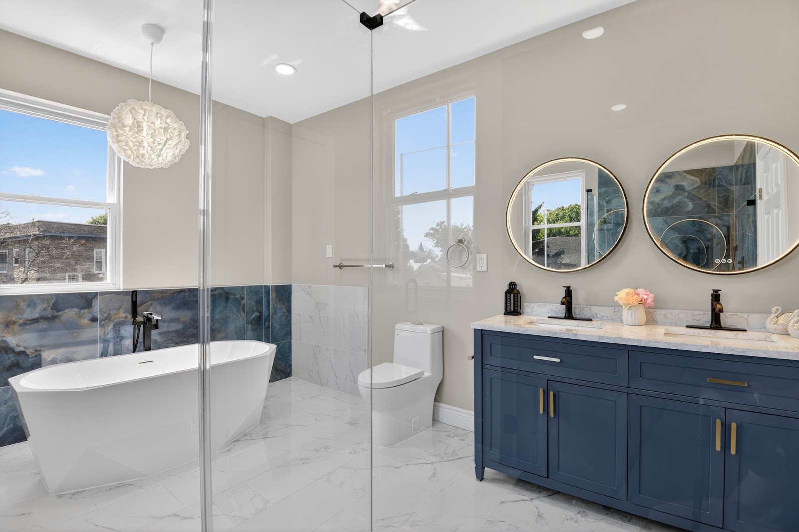 Luxury bathroom remodel with freestanding soaking tub, blue double vanity with gold hardware, and large marble tile floors — HousePro South Jersey