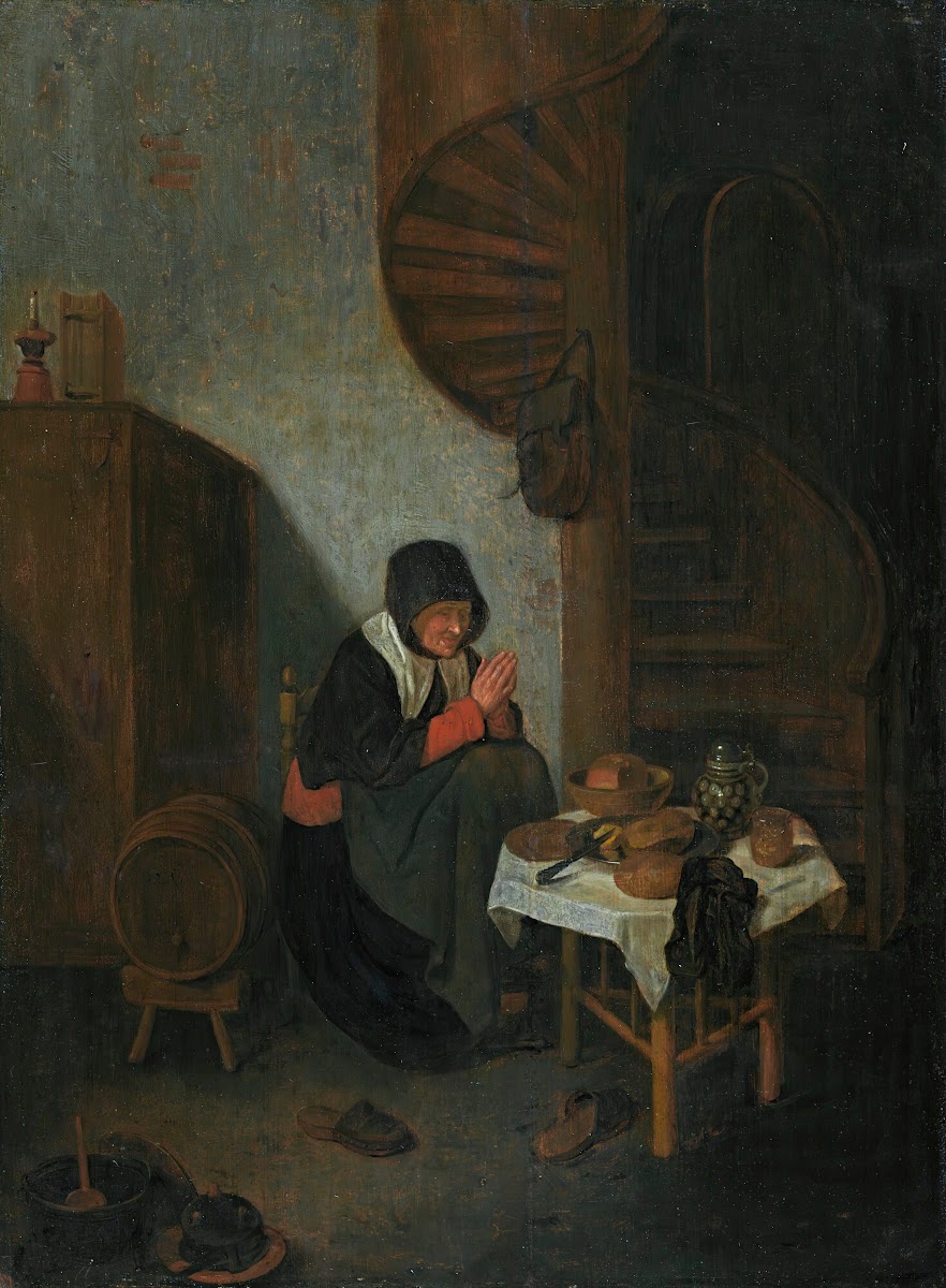 An old woman in an interior saying grace before a meal