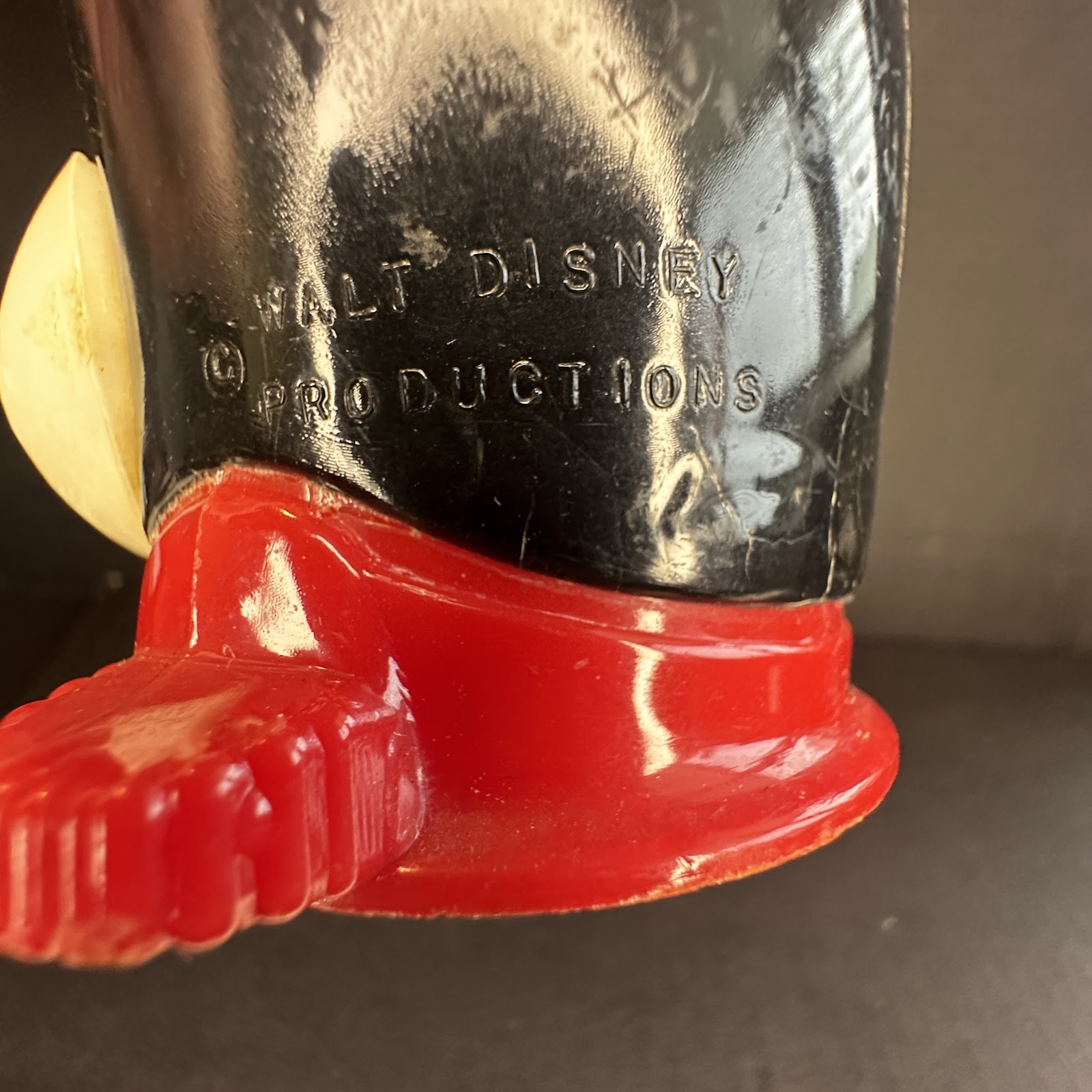 Vintage Mickey Mouse wind-up mechanical toy with molded black plastic figure on red base, embossed Walt Disney Productions copyright, mid-century design