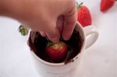 Sau khi được làm lạnh, lần lượt nhúng các trái dâu tây vào chocolate đen cho phủ đều thân trái dâu rồi để yên cho chocolate đông lại.
