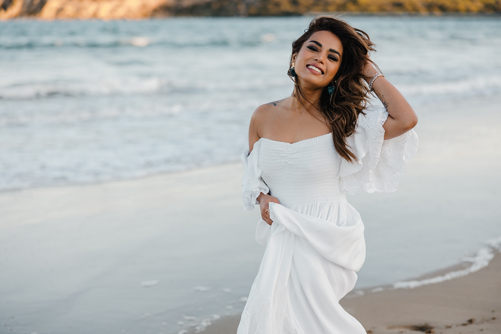 Parul smiling on the beach in a white dress