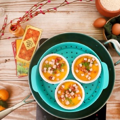 Sau 10 phút thì mở nắp ra, cho vào chén trứng 2 muỗng canh lòng đỏ trứng, rồi tiếp tục cho chả lụa và lạp xưởng hạt lựu lên trên, rắc thêm hành lá cắt nhỏ, hấp tiếp tục thêm 5 phút nữa thì tắt bếp.