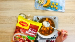 Khi hạt sen và thịt bò gần mềm, cho vào bí đỏ, nêm gia vị với ½ muỗng canh đường và 1 muỗng canh hạt nêm nấm hương Maggi. Khuấy nhẹ canh, sau cùng rắc hành lá cho thơm rồi tắt bếp.