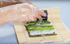 Với miếng rong biển lớn còn lại bạn cho vào mặt phẳng, lấy cơm dán nối chúng lại với nhau. Cho cơm vào miếng rong biển lớn, chừa lại một khoảng rong không có cơm. Tiếp đến cho dưa cải muối Nhật Bản vào với khoảng cách đều nhau. Sau đó cho cuộn sushi hoa anh đào vừa làm xong ở trên vào cuộn tròn lại. Put the big piece of seaweed on the chopping-board, use ricce to stick it with the rest small piece one. Spread rice on 1/5 the seaweed. After that, put the pickled leaf vegetable on then add the ume roll that had rolled above on and roll all of them together.