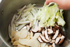 Làm nóng nồi hoặc chảo to với 1 muỗng canh dầu ăn, cho phần cọng cải thảo vào đảo tới khi phần này mềm thì thêm măng, nấm và phần lá cải thảo vào chung, nêm chút hạt nêm. Xào khoảng 3-4 phút hoặc đến khi các nguyên liệu này chín thì bạn lấy ra một tô riêng.