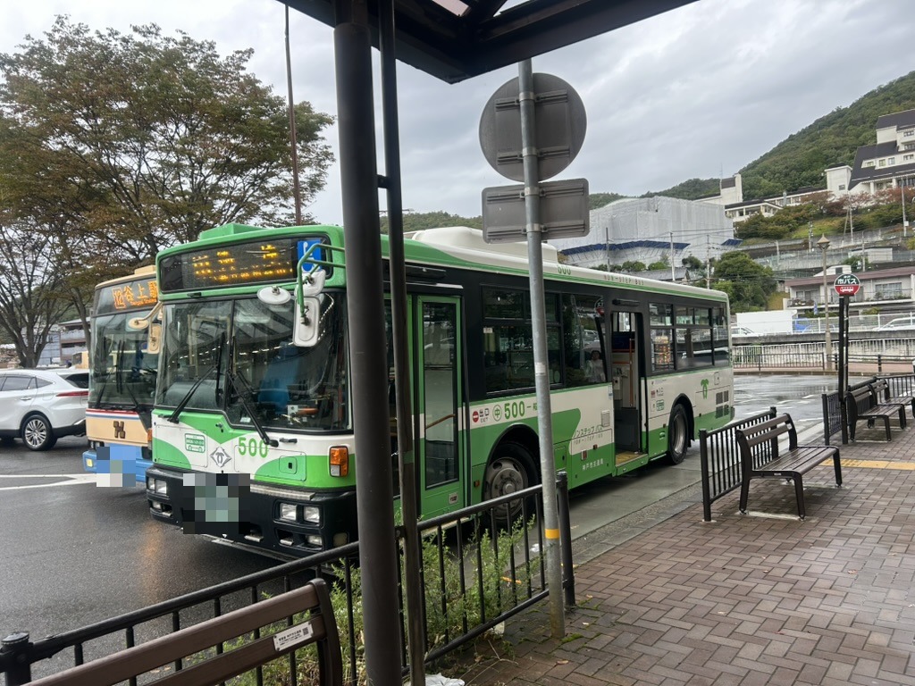 谷上駅のバス停に停まる市バスと、並んだベンチ