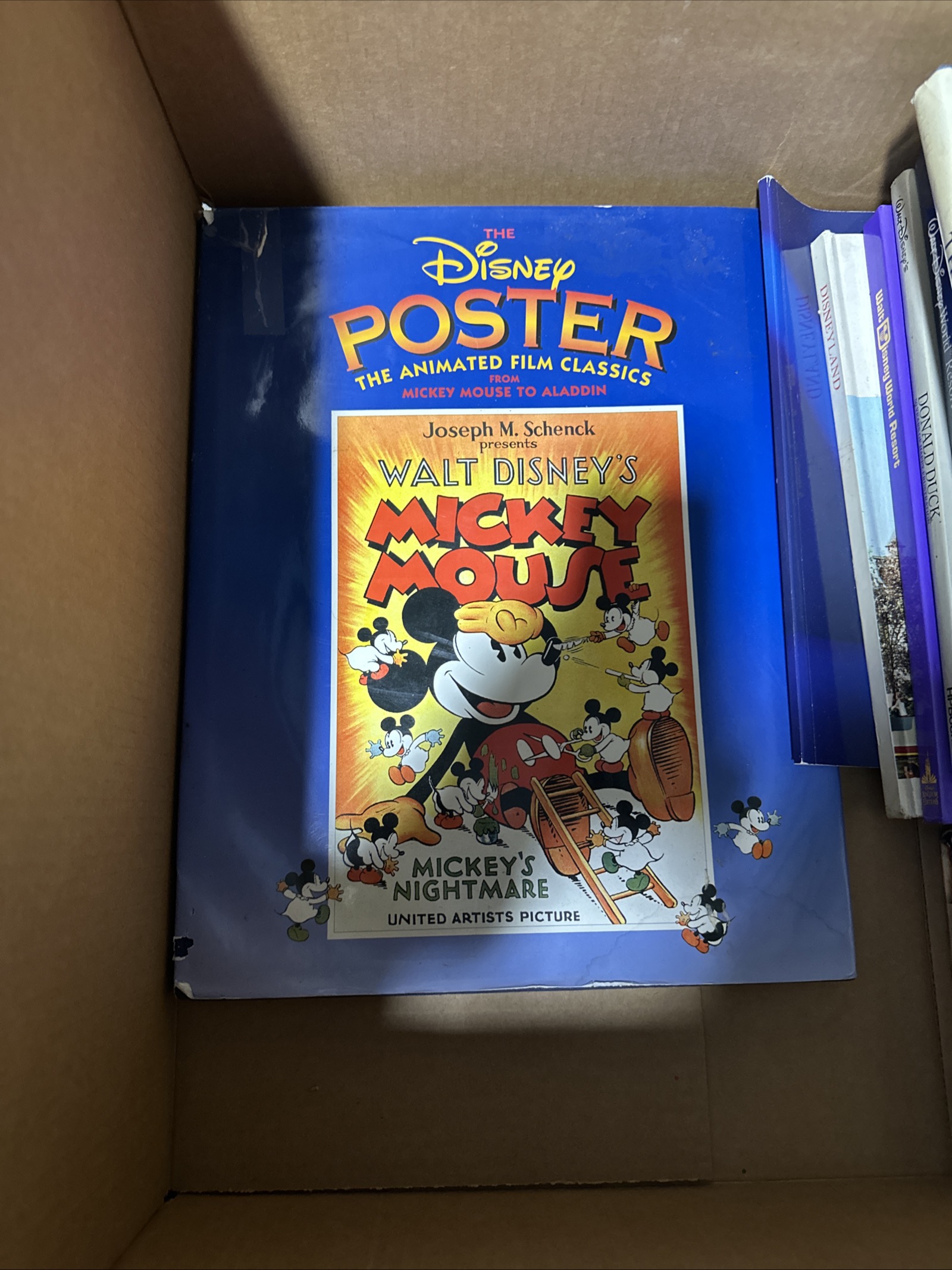 Large-format softcover art book with glossy blue cover, 11x14 inches, showing Disney animated film poster reproductions