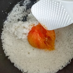 Cơm cạn, bạn mở nồi, dùng tay bóc nhanh lớp vỏ cà chua. Dùng dùng tán đều phần cà chua trộn đều với cơm, loại bỏ phần cuống.