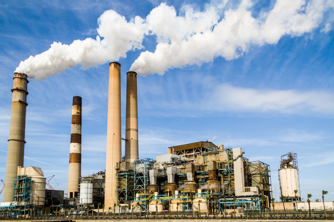 A factory power plant emitting plumes of white smokes