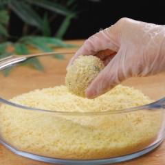 Dùng bao tay ấn dẹp cơm đã trộn, cho trứng cút vào giữa, sau đó bọc lại và vo viên chặt tay. Tiếp theo nhúng vào 100gr bột chiên xù, vo lại cho bột chiên xù bám chặt viên cơm. Lặp lại cho đến khi hết trứng cút hoặc cơm.