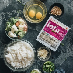 Rau củ (cà rốt, đậu Hà Lan, đậu que, khoai tây,...) tổng hợp, bạn có thể mua dạng đông lạnh rồi chỉ việc xả đông. Nếu dùng rau củ tươi, bạn chon bất cứ loại rau củ nào mình thích rồi làm sạch, thái hạt lựu cho dễ chiên nhé. Bắc một nồi nước lên bếp, trụng rau củ cho chín rồi xả ráo nước. Băm nhỏ hành lá và tỏi. Thấm khô đậu hũ bằng khăn giấy hoặc khăn sạch rồi cắt thành khối vuông nhỏ. Rắc muối và tiêu đều khắp các mặt đậu hũ.