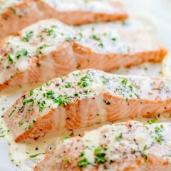 Cho cá hồi ra đĩa, rưới sốt kem chanh và rắc ít rau ngò lên trên rồi thưởng thức nào.