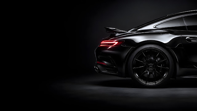 Glossy black high-end sports car rear quarter panel showcasing curved bodywork and a sleek red light bar against a dark gray backdrop.