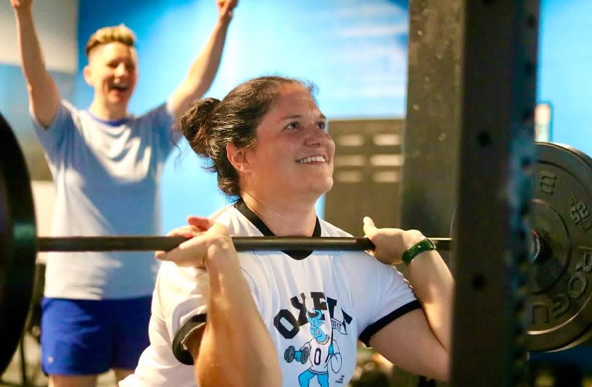 OxFit class cheering a member through a front squat
