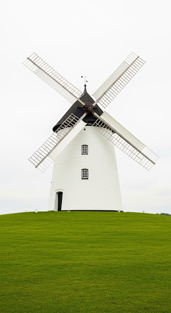 Traditional Historic Windmill in a Green Field Under an Overcast Sky - Free mobile Wallpaper