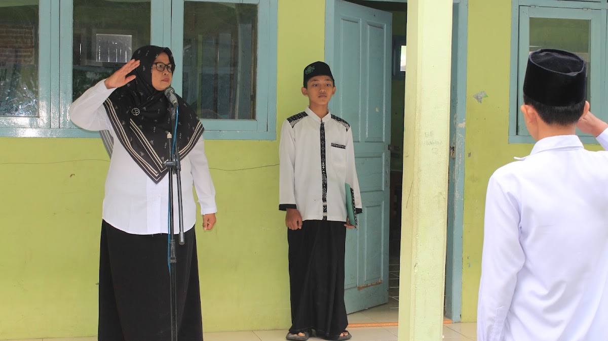 Pembina upacara memberi hormat di depan mikrofon didampingi ajudan