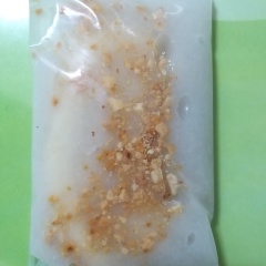 Lấy 1 cái muỗng cà phê, múc 1 muỗng đậu phộng đã giã nát cho lên mặt chuối. Gấp 2 mép bọc, tạo hình chữ nhật cho miếng kem chuối. Làm lần lượt cho hết số chuối.
