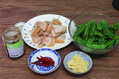 Thịt ba chỉ cạo sạch lông ở lớp da heo, rửa sạch, luộc trong nước sôi với 1 muỗng cà phê muối khoảng 5 phút rồi vớ ra thái lát mỏng. Trái đậu ván cắt bỏ 2 đầu, rửa sạch, chần sơ qua nước sôi khoảng 1-2 phút rồi vớt ra cắt đôi. Tỏi bóc vỏ, băm nhỏ.