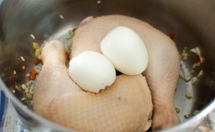 Bắc nồi lên bếp, cho dầu mè vào đun nóng rồi cho tỏi, gừng, ớt băm vào phi thơm, cho đùi gà cùng trứng lòng đào vào. Nêm nước tương, hắc xì dầu, giấm đen, đường phèn, nước. Đậy nắp và đun sôi nước. Vặn lửa liu riu và đun nhỏ lửa trong 20 phút cho đến khi gà chín hoàn toàn.