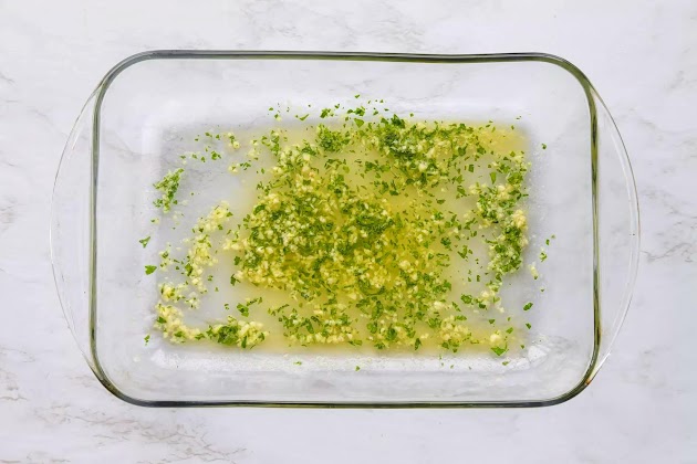 mantequilla derretida, sal, ajo machacado y perejil picado en una fuente para hornear