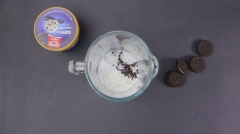 Cho lần lượt vào máy xay sinh tố gồm: 1 ly đá viên nhỏ, 30ml sữa tươi, 5g chocolate chip, 3 viên kem vani, 10ml siro chocolate và 1 cái bánh oreo. Mở máy và xay nhuyễn mịn tất cả.