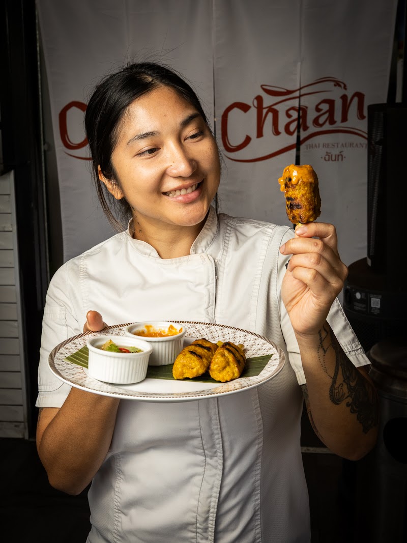 Chef Mew of Chaan Thai holding Kai Ta Krai lemongrass chicken skewers