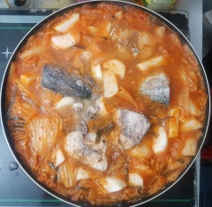Cho một chảo khác lên bếp, thêm vào chút dầu mè đợi chảo nóng. Cho kim chi vào chảo, nêm thêm chút đường và xào trong 3 phút. Cho nước vào ngập chảo kimchi và đun tiếp trong khoảng 5-7 phút. Vì mình thích ăn củ cải trắng nên bước này mình cho thêm củ cải trắng. (bạn nào không thích ăn cải trắng thì bỏ qua nguyên liệu này nhé). Khi nước đã sôi lại, bạn cho cá ngừ cùng hành tây và hành lá vào và tiếp tục đun.
