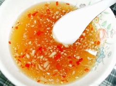 Cho vào chén 1 muỗng canh nước mắm, 1 muỗng canh đường, 1 muỗng canh giấm và 5 muỗng canh nước lọc, khuấy tan. Sau đó, cho tỏi và ớt băm vào trộn đều.