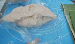 Cho thịt vào cối xay đánh tốc độ vừa cho đều khoảng 2 phút rưỡi, sau đó cho đá lạnh, bột nở, bột khoai tây đánh cho đều khoảng 1 phút, rồi bật tốc độ cao nhất đánh đến khi dẻo như hình là được. Trải miếng bọc thực phẩm rồi quét dầu để không bị dính. Cho chả lụa gà lên tạo thành hình trụ, đập cho xuống cho không còn lỗ khí.