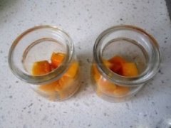 Ngâm lá gelatin trong sữa tươi để gelatin nở mềm. Cắt xoài thành từng miếng quân cờ, sau đó lấy một ít đem cho vào lọ đựng pudding.