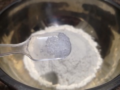 Cho bột vào thố lớn, thêm 1g muối và nước vào, dùng đũa khuấy đều. Sau đó dùng tay nhồi hỗn hợp bột thành khối đồng nhất, bọc màng thực phẩm ủ 1 tiếng đồng hồ. Sau khi ủ, chia chỗ bột thành 7 khối đều nhau, vê tròn.