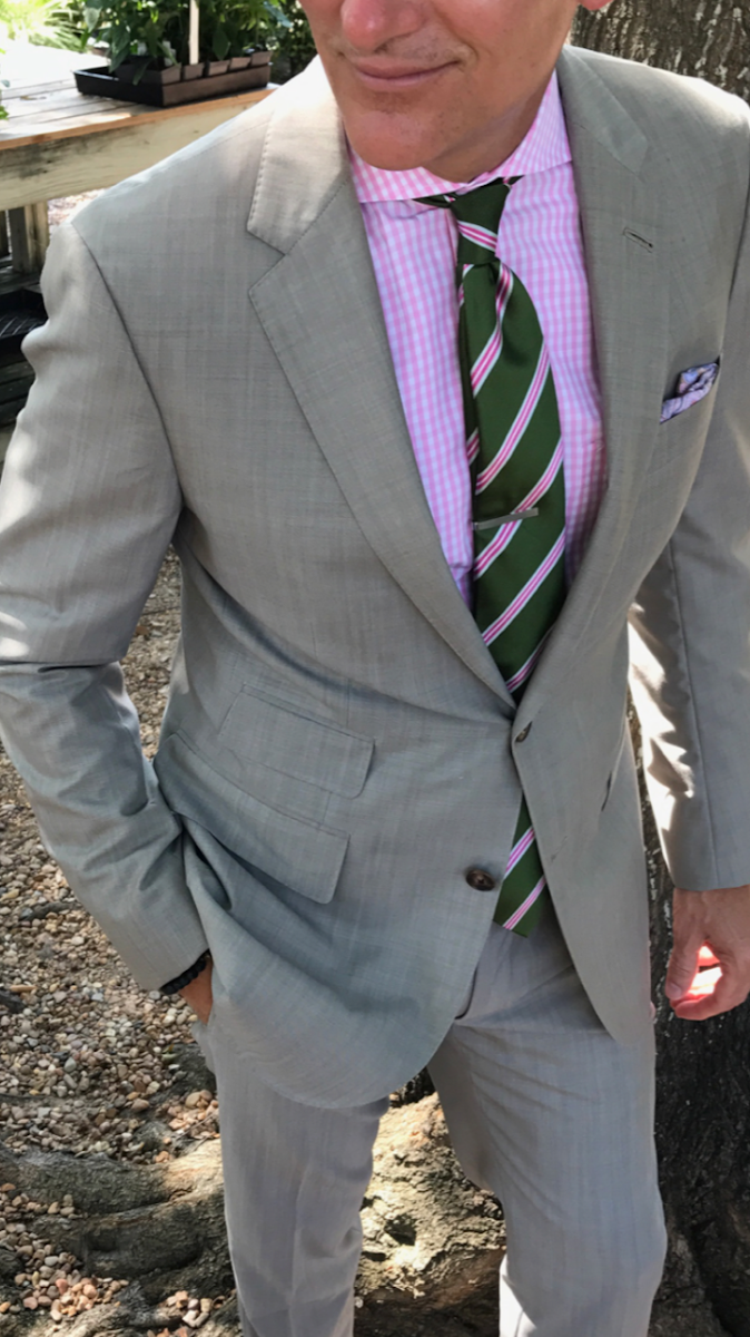 Groom wearing a light grey summer suit crafted from high twist tropical wool showing sharp tailored lines.