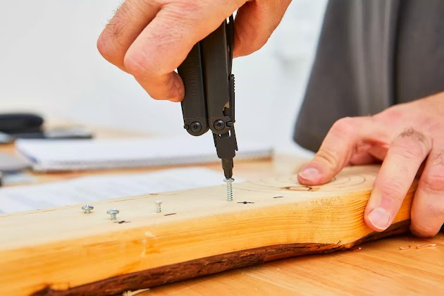 Persoon die de LEATHERMAN Wave Plus Multitool met premium vervangbare draadknipper gebruikt om schroeven te repareren