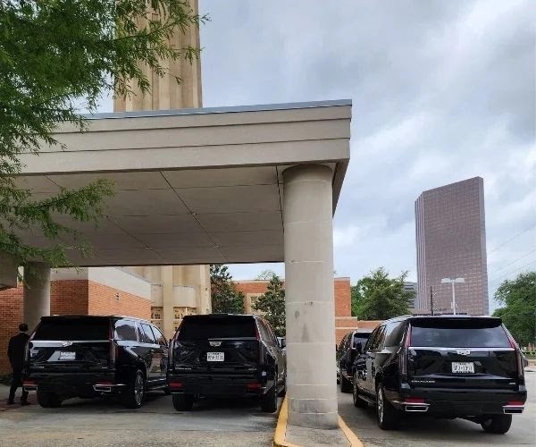 Three black executive SUVs parked under a covered building entrance in Houston