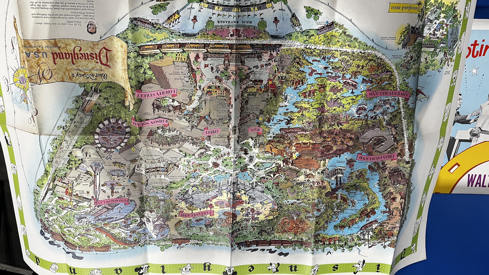 Large format vintage Disneyland park map from the 1960s–1970s showing illustrated bird's-eye view of the park with Disney characters and vibrant colors, showing typical fold wear