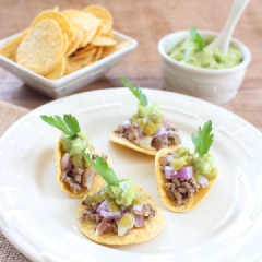 Cho hỗn hợp thịt xông khói, thịt bò lên những vỏ taco rồi cho lên trên hành tây xắt nhỏ, ớt, nước sốt kem bơ và một lá rau ngò tây trang trí.