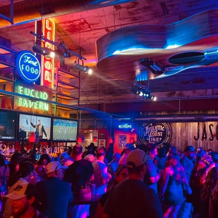 Interior view of Jason Aldean's with rustic decor, wooden tables, and live music stage.