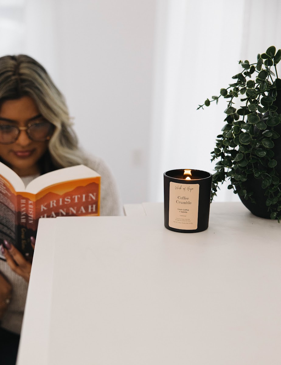 Woman reading a book by candlelight with a Wick of Hope candle