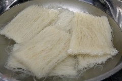 Đun bột điều với dầu ăn trên bếp nhỏ lửa để được dầu điều. Ngâm bún khô vào nước cho bún mềm và nở ra.