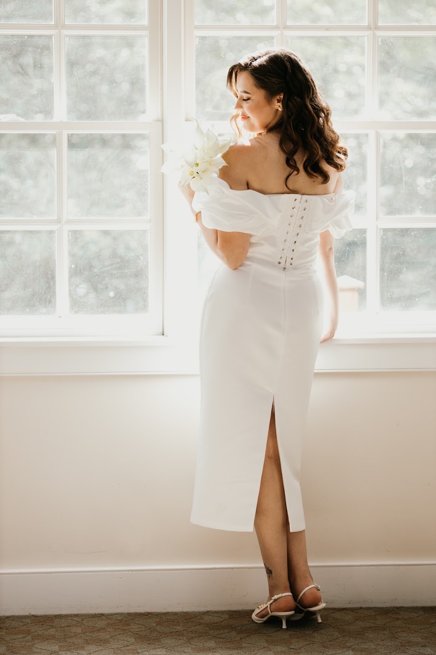 Bride at the window with calla lilies — natural light bridal portrait