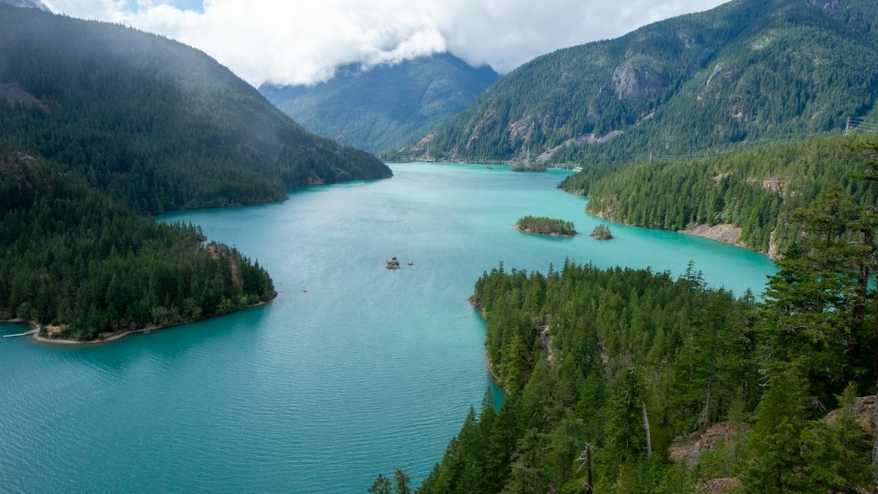 Vivid turquoise glacial water of Diablo Lake winding between steep granite Cascade peaks from SR-20 overlook