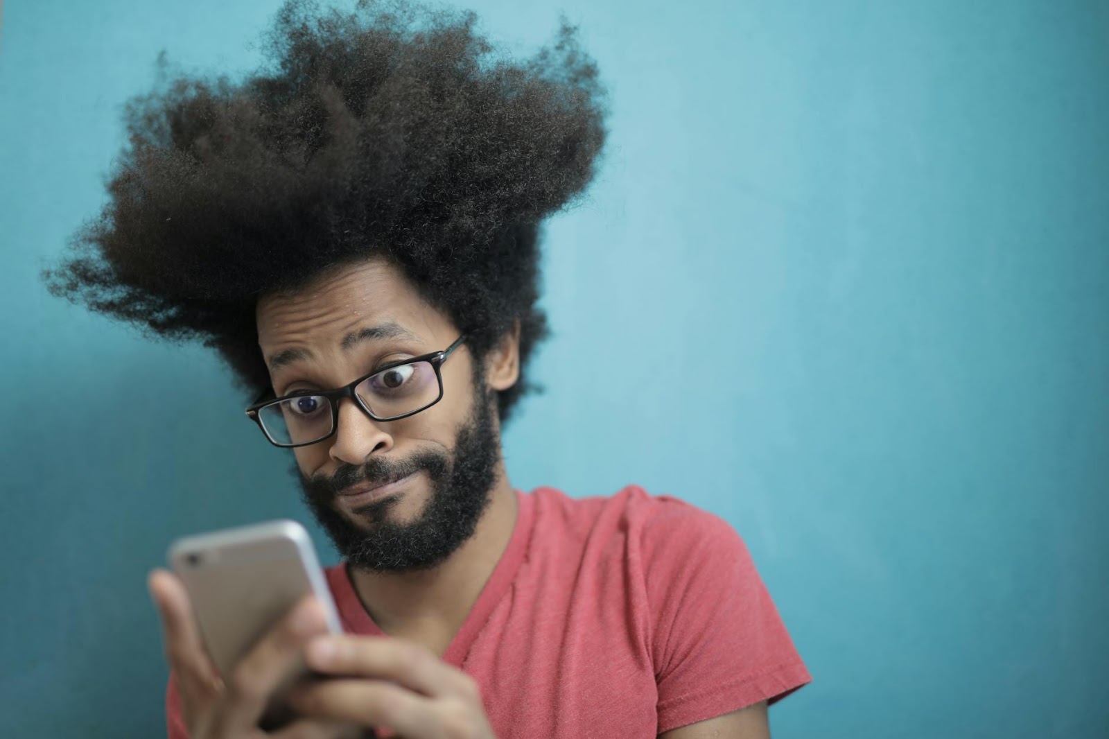 A person looking at a smartphone with a surprised and concerned expression, reflecting the consumer's reaction to rising Future Tech Prices 2026.