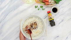 Trong một tô lớn, trộn đều 500gr cơm nguội với 2 muỗng canh nước tương Maggi nắp đỏ, 1/2 muỗng cà phê hạt nêm Maggi và 1 muỗng canh tương ớt Hàn Quốc rồi ướp trong 10 phút.