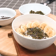Cho sữa chua vào tô, rắc hạt bí và hạt chia vào. Cuối cùng xếp chuối đã cắt lát lên xung quanh chén.